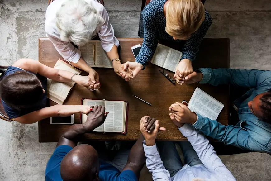 people holding hands around a table